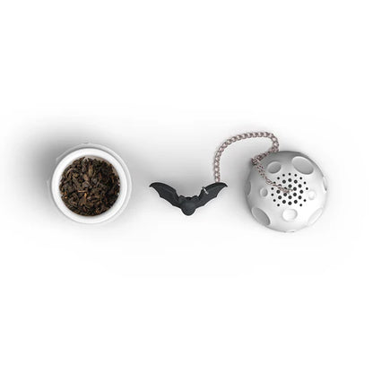 Tea infuser shaped like a bat and a moon container of tea leaves on a white background